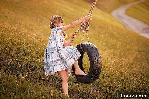 Upcycled Tire Swing hanging from a tree in a lush green backyard