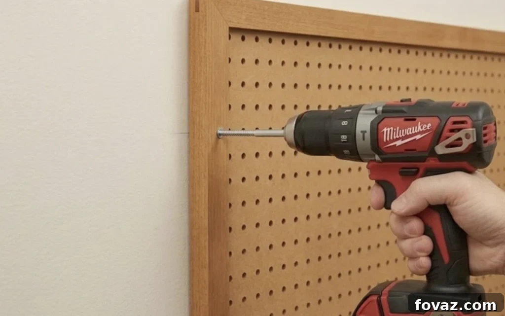 Person mounting a pegboard with a power drill