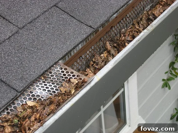 A person cleaning leaves and debris out of a home's gutter system.